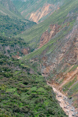 Spectacular and amazing beautiful panorama of the Andes Mountains in the Colca Canyon, Peru. Geological formation of a huge cliff. Green background and river.