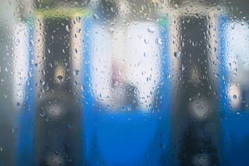 Abstraktes Motiv mit Regentropfenmuster vor blau-weißen Tanksäulen an Tankstelle bei Regen am...
