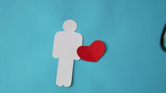 doctor hand holding stethoscope with man figure from white paper and heart symbol on blue background. american heart month in February