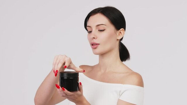 Portrait of a charismatic young woman using face creams. Concept of fresh moisturized skin, beautiful cosmetic face, happy healthy model. A young brunette takes care of her skin.