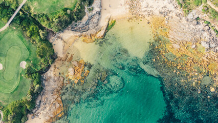 Obraz premium Image taken with a drone at a zenith angle of a beach showing the green trees, the sand and the turquoise sea. Small and quiet beach in Sydney, Australia