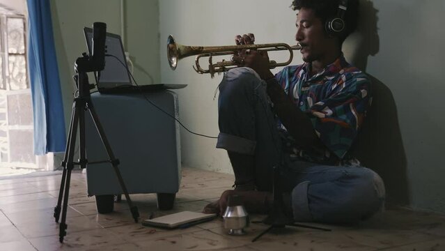 Young man playing the trumpet, recording improvisation solo at home studio
