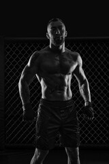 Fototapeta na wymiar The dramatic black white image of the MMA fighter. Photography in a real octagon. Brutal fighter