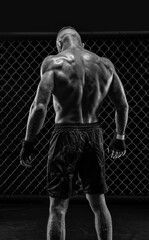 Fototapeta na wymiar The dramatic black white image of the MMA fighter. Photography in a real octagon. Brutal fighter