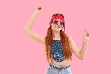 Stylish young hippie woman in sunglasses dancing on pink background