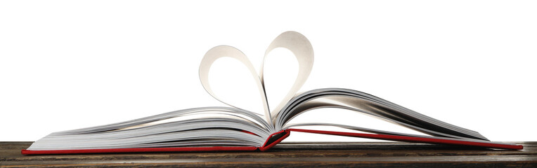 Open book with pages folded in heart on wooden table against white background