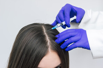 A young woman receiving injections into the scalp for hair growth. PRP therapy for hair Loss....