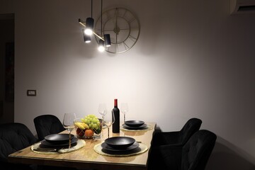 Table with plates, fruits, glasses and bottle of wine in room