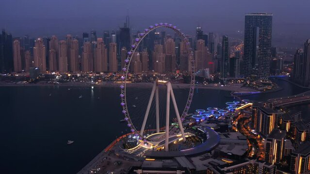 Aerial Eye of Dubai Ferris wheel city lights twilight, jbr beach in background