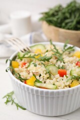 Fototapeta na wymiar Cooked bulgur with vegetables in bowl on white wooden table, closeup