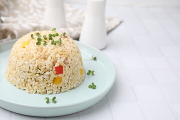 Delicious bulgur with vegetables and microgreens on white table, closeup. Space for text
