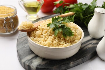 Delicious bulgur with parsley in bowl served on table, closeup