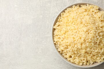 Delicious bulgur in bowl on gray table, top view. Space for text
