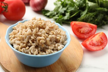 Delicious pearl barley in bowl on white table, closeup
