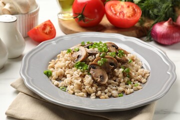 Delicious pearl barley with onion and mushrooms on white table, closeup