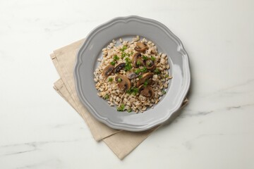 Delicious pearl barley with onion and mushrooms on white marble table, top view