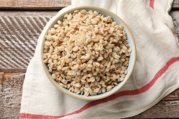 Delicious pearl barley in bowl on wooden table, top view