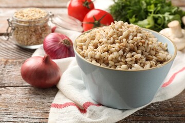 Delicious pearl barley in bowl served on wooden table, closeup