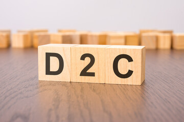 three wooden cubes on a gray background, with the abbreviation D2C - Direct to Consumer