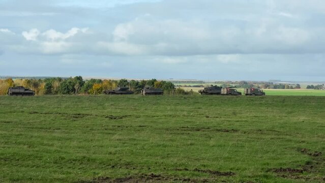 A Challenger II 2 FV4034 main battle tank, Warrior FV512 MRV and a Bulldog FV432 moving slowly, directed to stationary positions in a field. Wilts UK