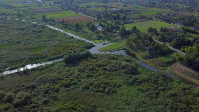 Beautiful nature ecosystem with small pond, lake with blue sky and forest and land in the distance in national park Obedska bara seen from aerial drone