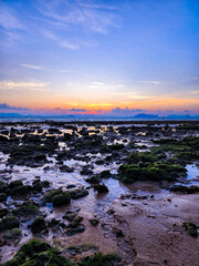 Rocks shore the beach during the sun sets