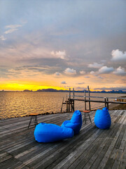 Empty beach bean bag chair on wooden balcony at sunset