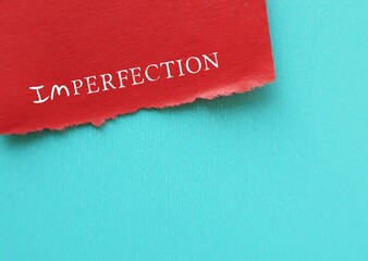 Red paper on blue copy space background with handwritten IMPERFECTION, concept of  embracing...
