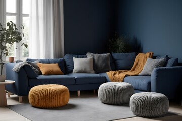 A dark blue corner sofa next to knitted puffs. Interior design of a modern living room in the Scandinavian style.
