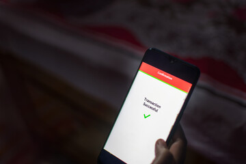 Woman Using Mobile Phone App To Authenticate Bank Transfer.