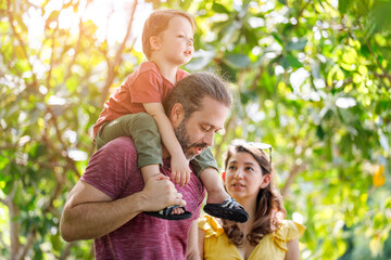 Happy Caucasian family spending time traveling together, green trees in sunlight.