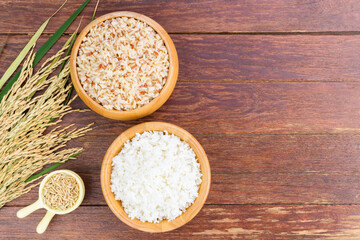 White rice or jasmine rice and brown rice in a wooden bowl with yellow ears of rice placed on a...