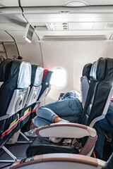Woman sleeping in airplane with arms crossed, close-up.