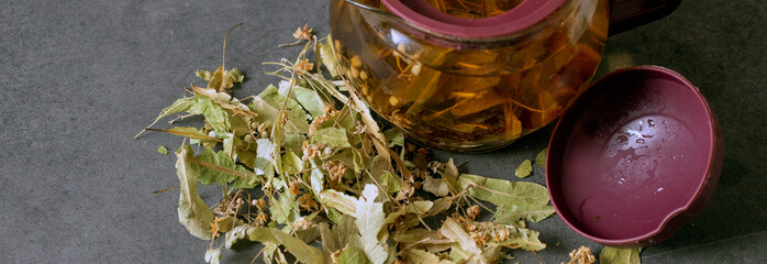 Natural linden tea for cold and flu stands ready to drink in a teapot on the ground,