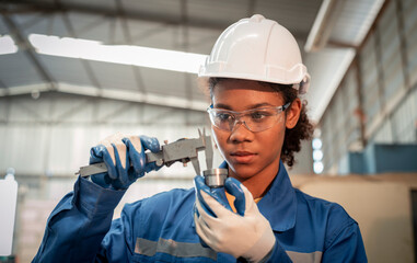 Engineer or factory worker wearing safety uniform under measuring a metal part with a digital...