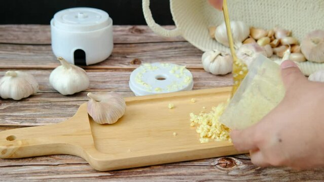 A man's hand is pouring the crushed garlic into a wooden plate.