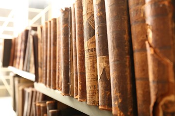 Different old books on shelf in library, closeup
