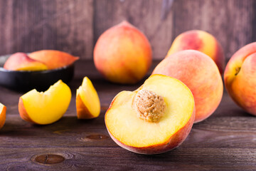 Fototapeta na wymiar Fresh peaches sliced and whole on a wooden table. Organic vitamin food.