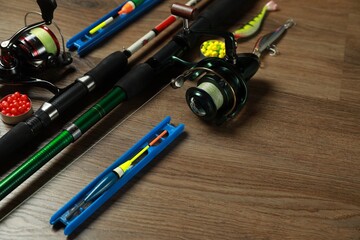 Spinning rods and fishing tackle on wooden background, closeup