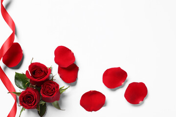 Fototapeta na wymiar Beautiful red roses, petals and ribbon on white background, top view. Space for text
