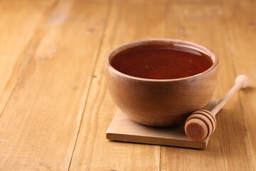 Delicious honey in bowl and dipper on wooden table. Space for text