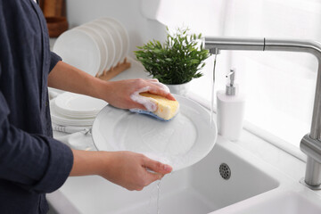 Woman washing plate at sink in kitchen, closeup - obrazy, fototapety, plakaty