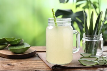 Fresh aloe juice in mason jar with straw and leaves on wooden table outdoors, closeup