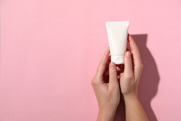 Woman with tube of hand cream on pink background, top view. Space for text
