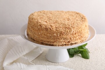 Delicious Napoleon cake and mint on beige table, closeup