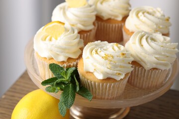 Delicious lemon cupcakes with white cream and mint on table, closeup