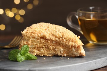 Piece of delicious Napoleon cake served on table, closeup