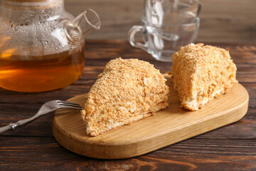 Pieces of delicious Napoleon cake served on wooden table, closeup