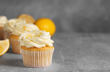 Delicious cupcakes with white cream and lemon zest on gray table, closeup. Space for text
