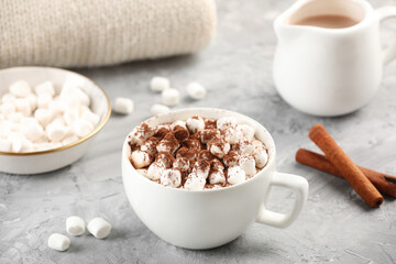 Cup of aromatic hot chocolate with marshmallows, cocoa powder on gray table, closeup